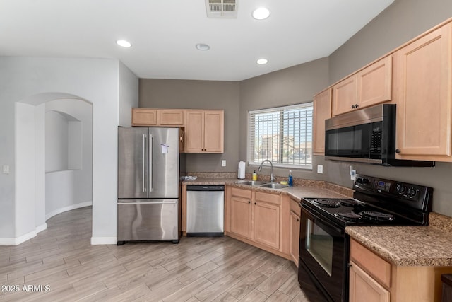 kitchen with light brown cabinets, visible vents, a sink, stainless steel appliances, and light wood-type flooring