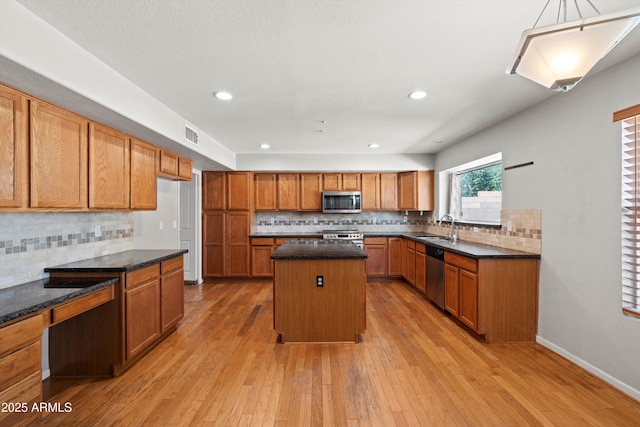 2024 N 125th Ave, Avondale, AZ 85392 - kitchen with appliances with stainless steel finishes, decorative backsplash, a center island, brown cabinetry, and light wood-type flooring