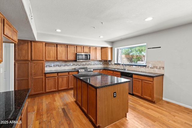 2024 N 125th Ave, Avondale, AZ 85392 - kitchen with stainless steel appliances, brown cabinets, light wood-style floors, backsplash, and dark stone countertops