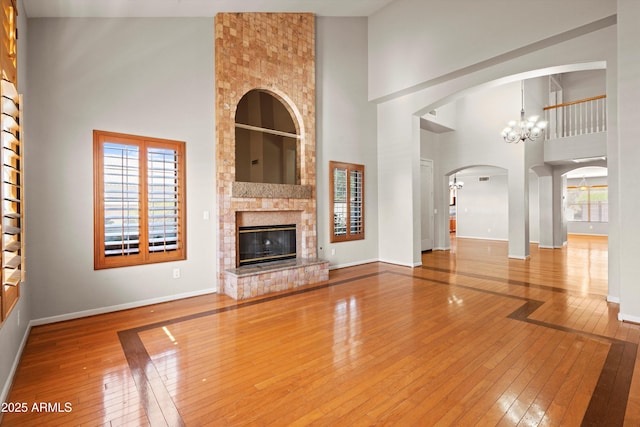 2024 N 125th Ave, Avondale, AZ 85392 - unfurnished living room featuring a high ceiling, hardwood / wood-style flooring, a chandelier, healthy amount of natural light, and a fireplace