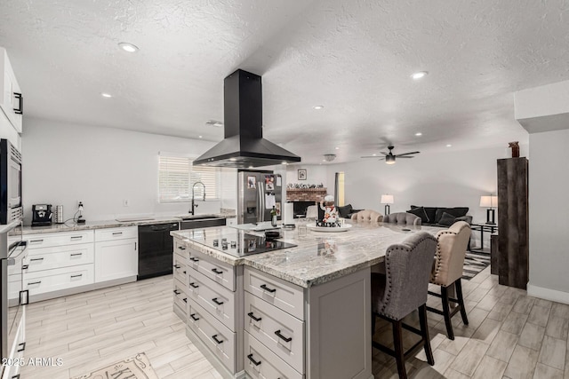 505 S S Rdg, Mesa, AZ 85204 - kitchen with black appliances, island exhaust hood, a breakfast bar area, light stone counters, and a textured ceiling
