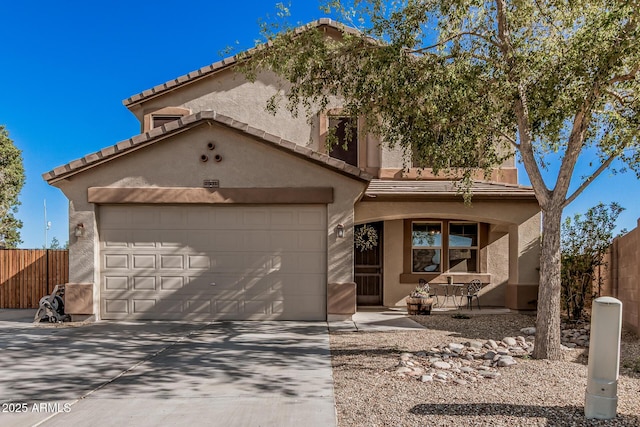 view of front of property with stucco siding, a tile roof, concrete driveway, and fence
