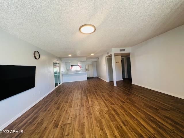 unfurnished living room with a textured ceiling and dark hardwood / wood-style flooring