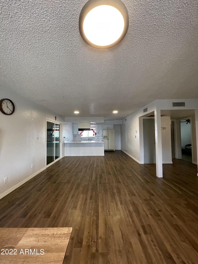 unfurnished living room with a textured ceiling and dark hardwood / wood-style floors