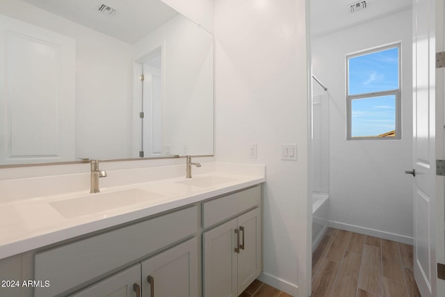 bathroom with hardwood / wood-style flooring, vanity, and tub / shower combination