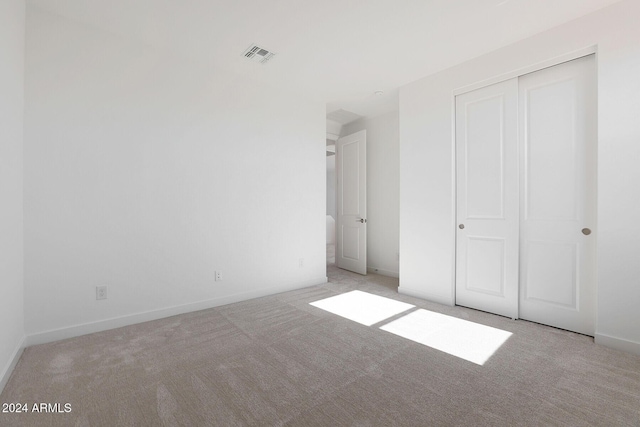 unfurnished bedroom with light carpet and a closet