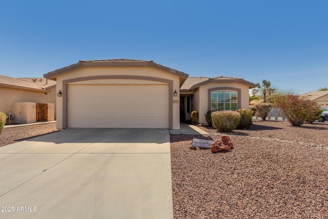 view of front facade featuring a tiled roof, a garage, driveway, and stucco siding