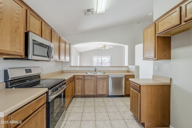 16077 W Larkspur Dr, Goodyear, AZ 85338 - kitchen with stainless steel appliances, arched walkways, a sink, vaulted ceiling, and light countertops
