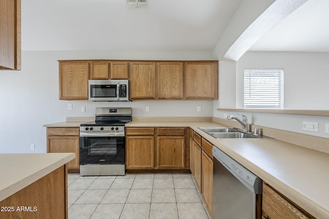 16077 W Larkspur Dr, Goodyear, AZ 85338 - kitchen with stainless steel appliances, a sink, light countertops, light tile patterned flooring, and brown cabinetry