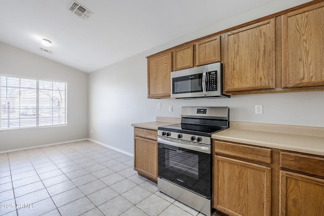 16077 W Larkspur Dr, Goodyear, AZ 85338 - kitchen featuring stainless steel appliances, lofted ceiling, light countertops, brown cabinetry, and baseboards