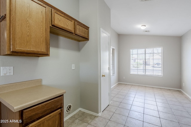 16077 W Larkspur Dr, Goodyear, AZ 85338 - kitchen featuring brown cabinetry, light tile patterned flooring, baseboards, and light countertops