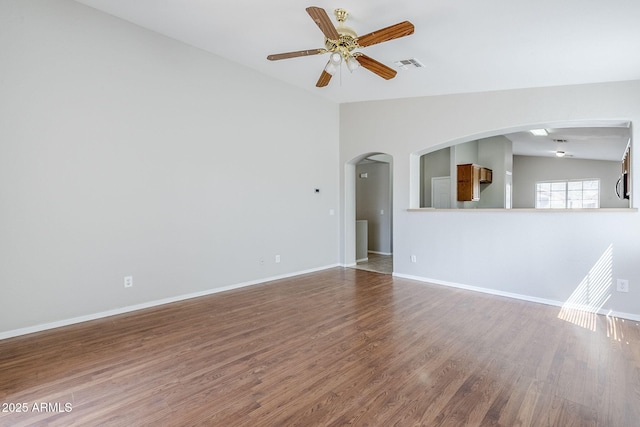 16077 W Larkspur Dr, Goodyear, AZ 85338 - unfurnished living room with vaulted ceiling, wood finished floors, ceiling fan, arched walkways, and baseboards