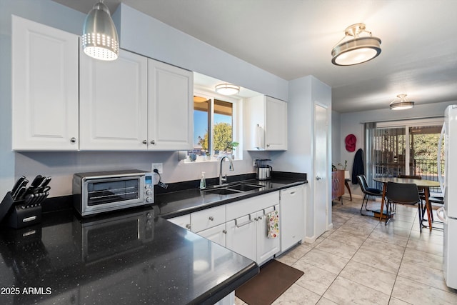 kitchen with white appliances, sink, light tile patterned floors, white cabinets, and hanging light fixtures