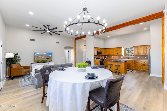 dining room with light hardwood / wood-style flooring, a high ceiling, and ceiling fan with notable chandelier