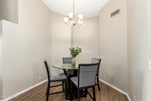 dining space featuring dark hardwood / wood-style floors and an inviting chandelier