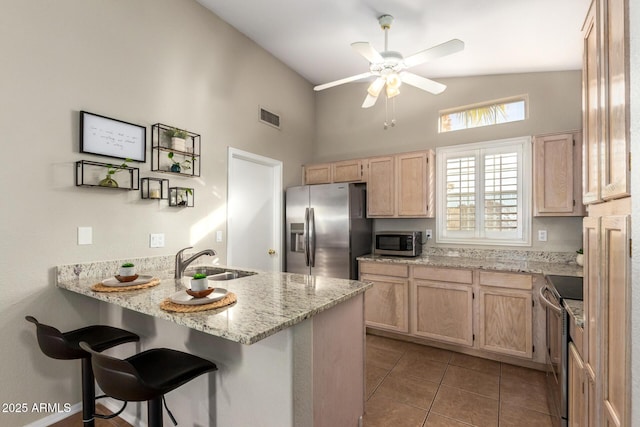 kitchen with light brown cabinets, sink, a breakfast bar area, kitchen peninsula, and stainless steel appliances