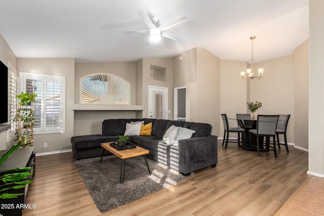 living room with lofted ceiling, wood-type flooring, and ceiling fan with notable chandelier