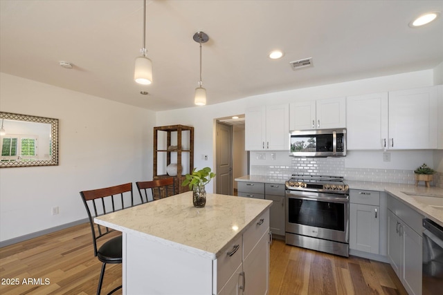7430 E Chaparral Rd Unit A222, Scottsdale, AZ 85250 - kitchen featuring stainless steel appliances, gray cabinetry, tasteful backsplash, a breakfast bar area, and recessed lighting