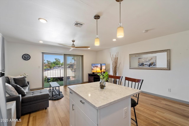 7430 E Chaparral Rd Unit A222, Scottsdale, AZ 85250 - kitchen with a kitchen breakfast bar, a kitchen island, light wood-style floors, decorative light fixtures, and open floor plan