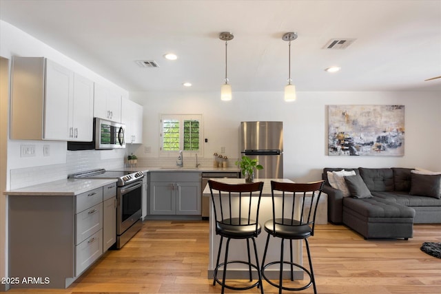 7430 E Chaparral Rd Unit A222, Scottsdale, AZ 85250 - kitchen featuring appliances with stainless steel finishes, gray cabinetry, a sink, light wood-style flooring, and a breakfast bar area