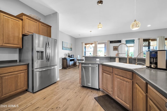 kitchen featuring sink, hanging light fixtures, stainless steel appliances, light hardwood / wood-style floors, and a chandelier