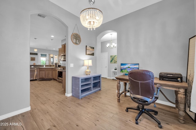 office space with an inviting chandelier, sink, and light hardwood / wood-style floors