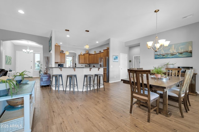 dining area with a chandelier, sink, and light hardwood / wood-style flooring