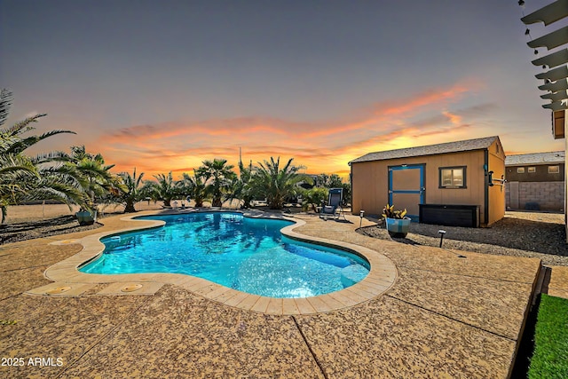 pool at dusk featuring an outdoor structure and a patio area