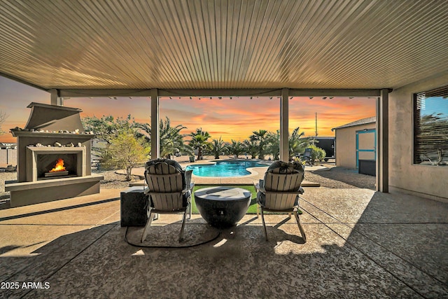 patio terrace at dusk featuring exterior fireplace