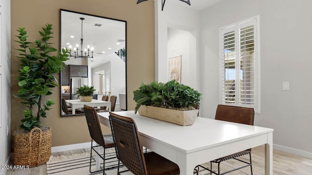 dining space with light wood finished floors, baseboards, and a chandelier