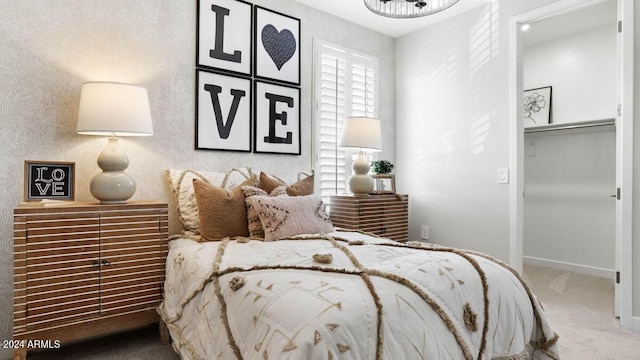 carpeted bedroom featuring baseboards and a walk in closet