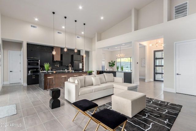 living room featuring light tile patterned floors, sink, a high ceiling, and a notable chandelier