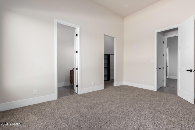 unfurnished bedroom featuring carpet, ensuite bath, and a walk in closet