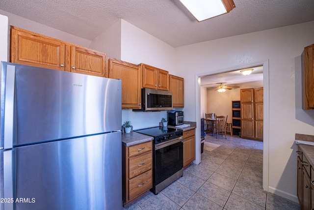 17810 N 34th Pl, Phoenix, AZ 85032 - kitchen featuring stainless steel appliances, light tile patterned floors, a textured ceiling, brown cabinetry, and a ceiling fan