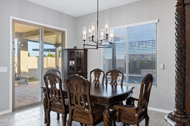 dining space with wood finish floors, an inviting chandelier, and baseboards