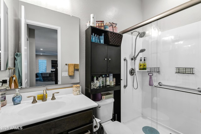 bathroom featuring toilet, a shower stall, and vanity