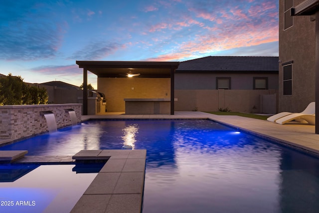 pool at dusk featuring a fenced in pool, a patio, outdoor dry bar, fence, and exterior kitchen