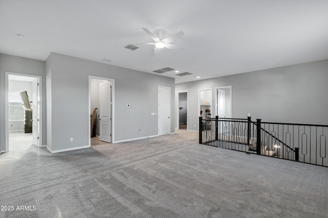 carpeted empty room featuring a ceiling fan, visible vents, and baseboards