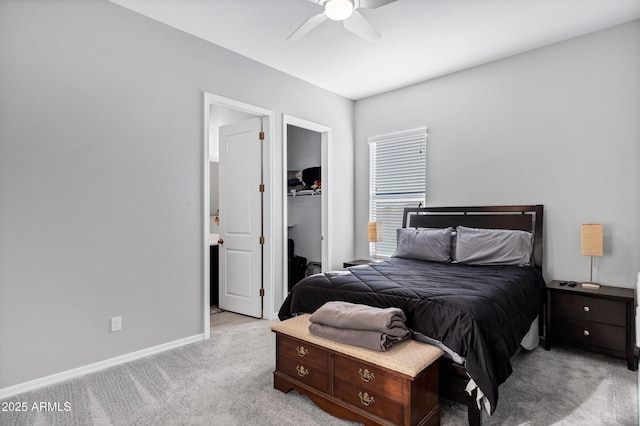 bedroom featuring light carpet, a ceiling fan, baseboards, a closet, and a walk in closet