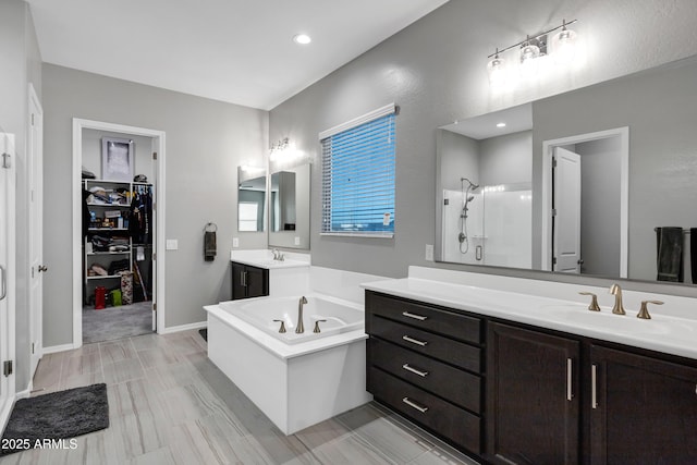 bathroom featuring a garden tub, two vanities, a spacious closet, a sink, and a shower stall