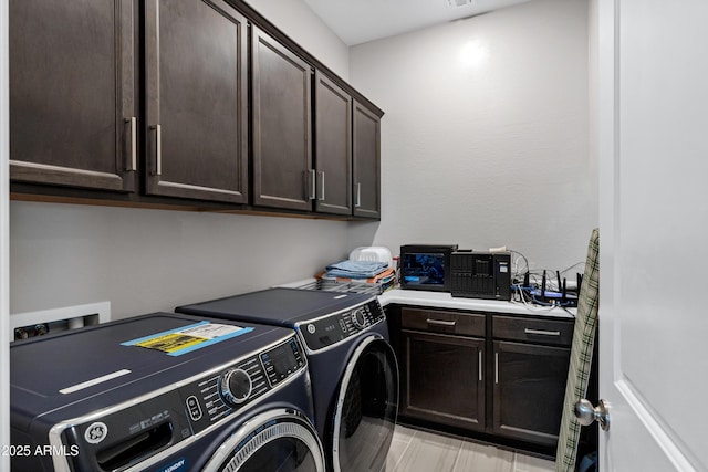 clothes washing area with visible vents, washing machine and clothes dryer, and cabinet space