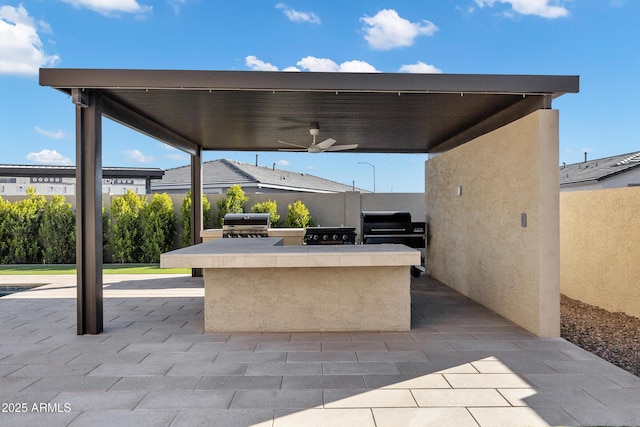 view of patio with ceiling fan, outdoor wet bar, an outdoor kitchen, and area for grilling