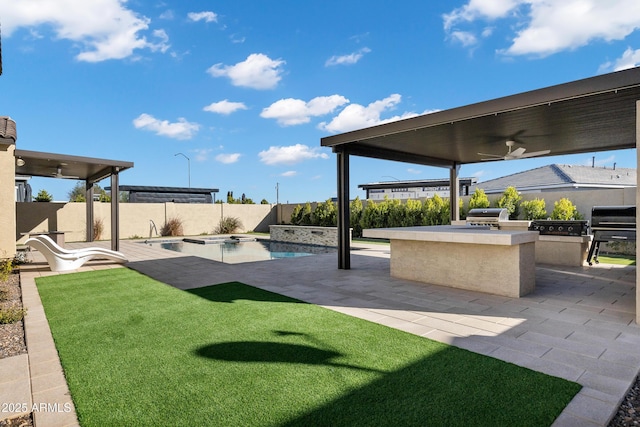 view of patio featuring a hot tub, a fenced in pool, a fenced backyard, grilling area, and exterior kitchen