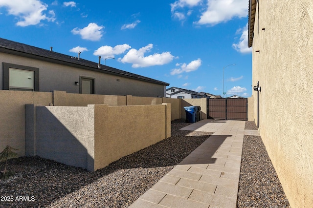 view of side of property with a gate, fence, and stucco siding