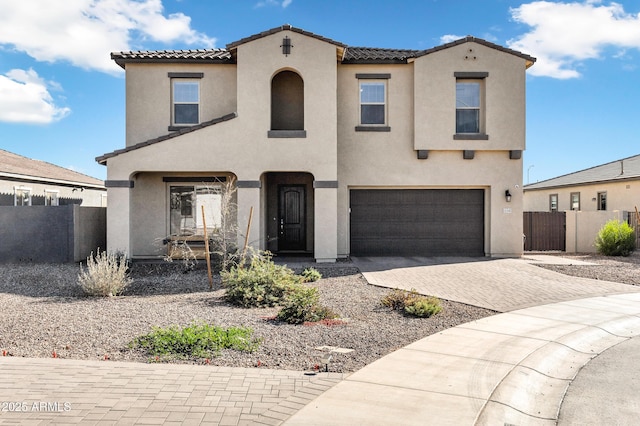 mediterranean / spanish house with a tile roof, fence, and stucco siding