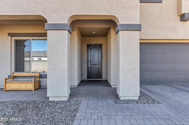 property entrance featuring decorative driveway and stucco siding