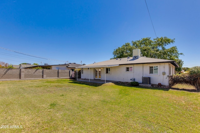 back of house with fence, central AC unit, stucco siding, a lawn, and french doors