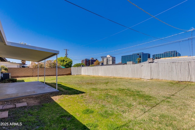 view of yard with a fenced backyard, central AC unit, and a patio