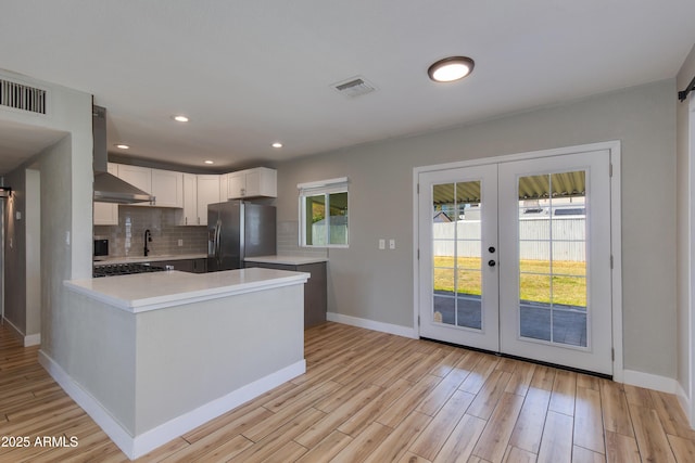 kitchen with light countertops, visible vents, range hood, stainless steel refrigerator with ice dispenser, and french doors