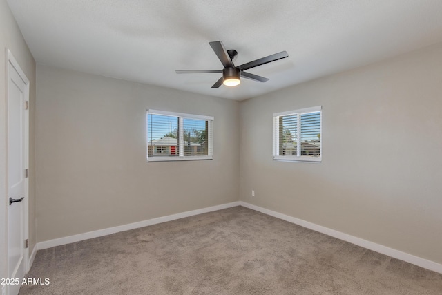 carpeted spare room featuring baseboards and a ceiling fan